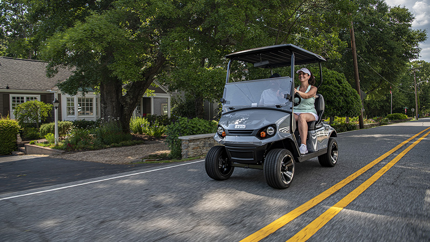 A couple driving their E-Z-GO Express S2 down a street.