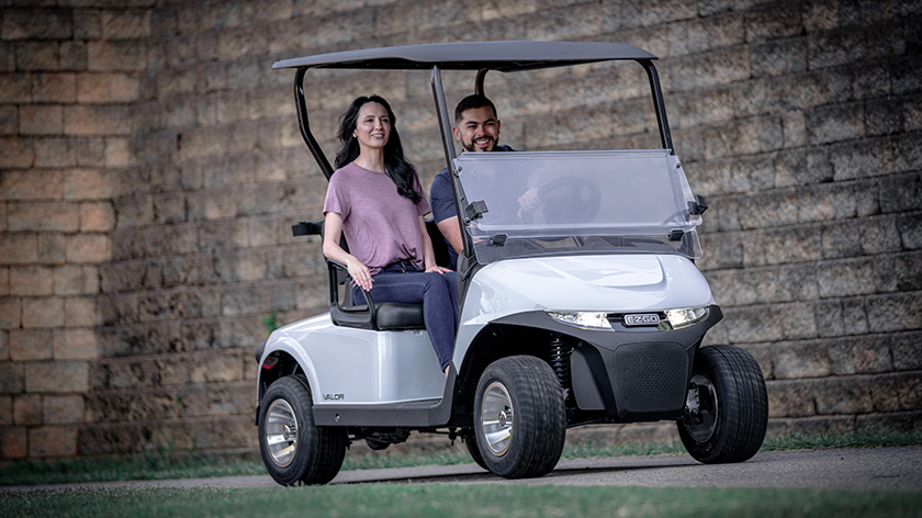 A couple driving an E-Z-GO golf cart.