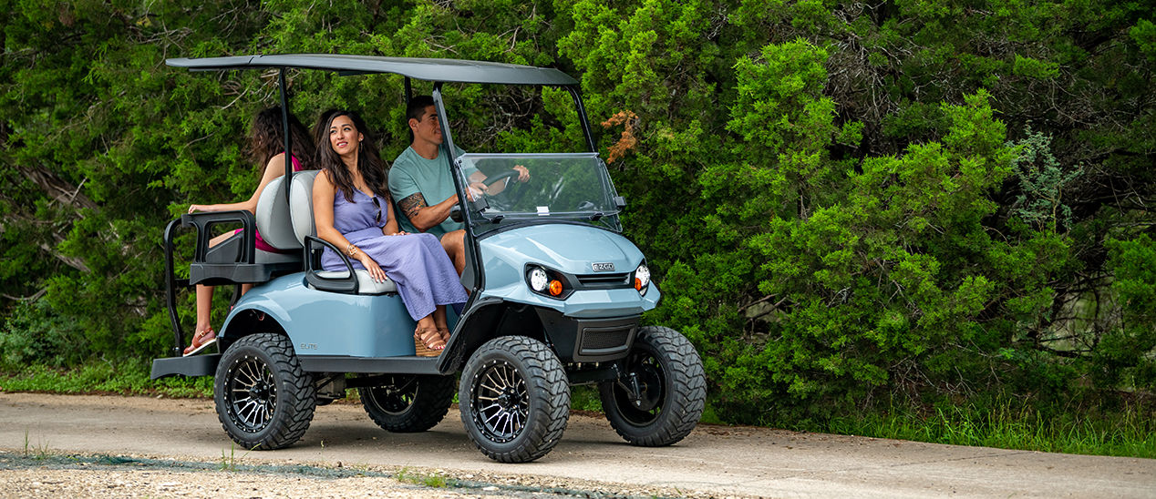 Family driving an E-Z-GO vehicle down a trail.