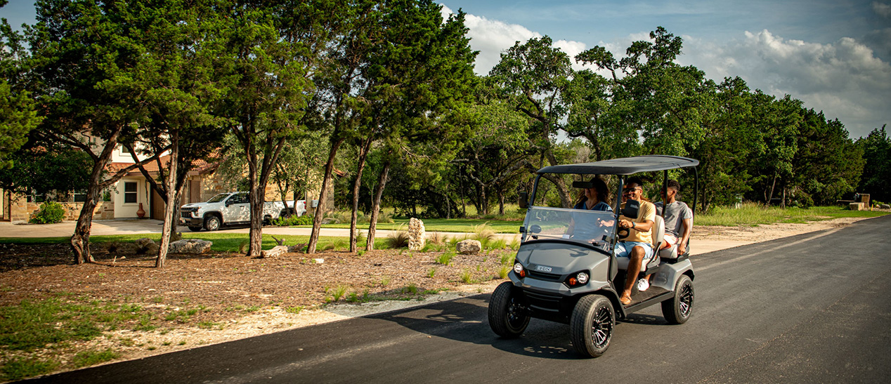 A group of friends driving down a road in their E-Z-GO.