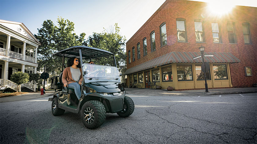 Two women driving an E-Z-GO Freedom RXV down a street.